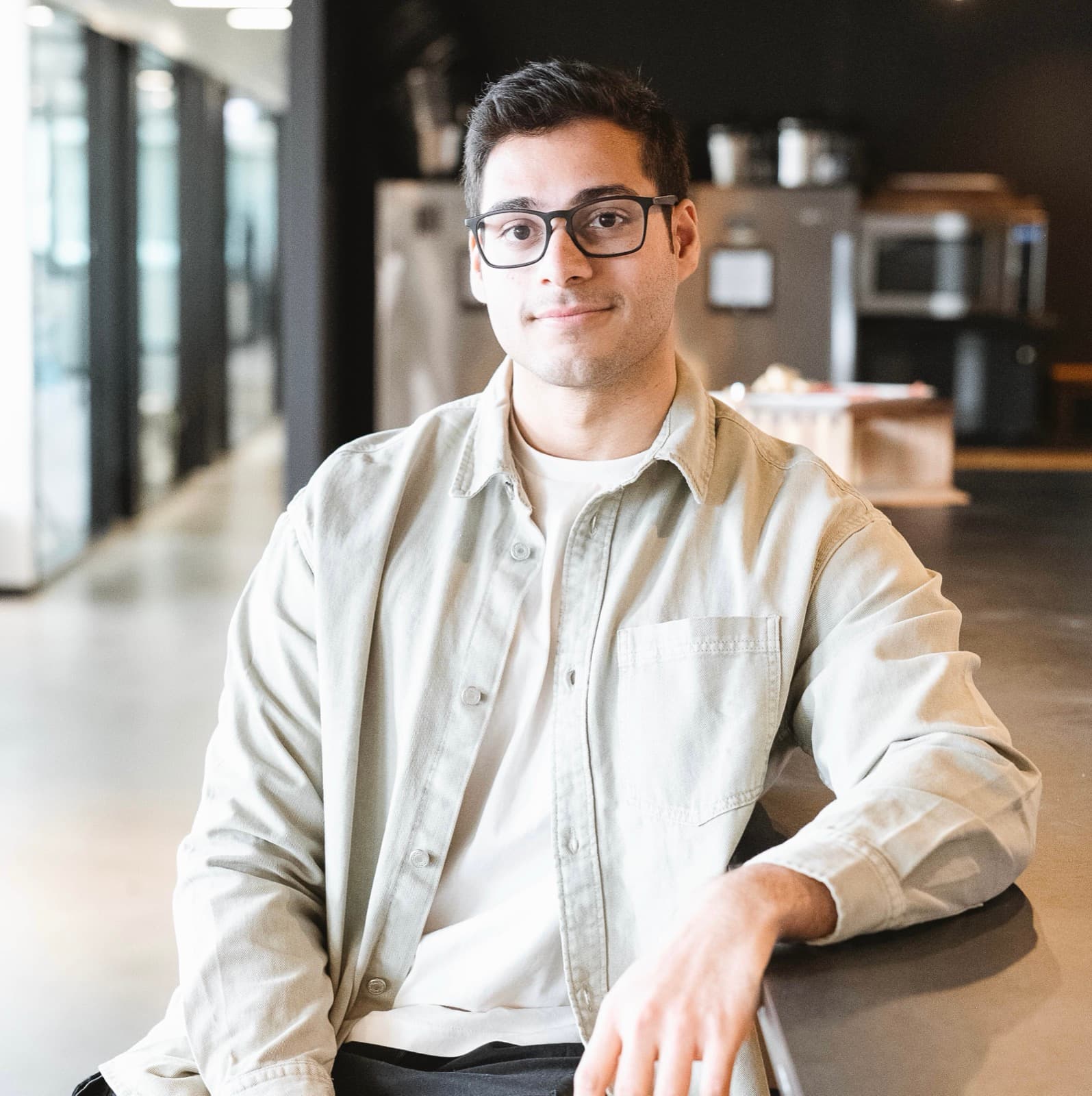 Aswin sitting at a table in an office, smiling